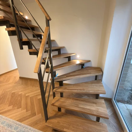 Elegante Holztreppe mit Metallgeländer offen und modern in hellem Zuhause