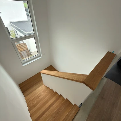Modernes helles Treppenhaus mit Holzboden großen Fensterblick und einer eleganten Holzgeländerung