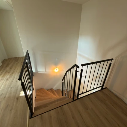 Moderne Holztreppe mit schwarzen Metallgeländern und hellen Wänden in einem stilvollen Wohnbereich