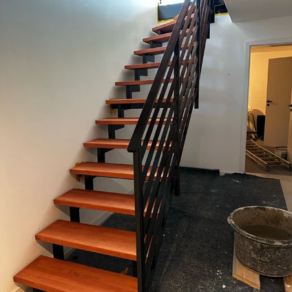 Hochwertige Holztreppe mit kontrastierendem schwarzem Metallgeländer in einem Innenraum