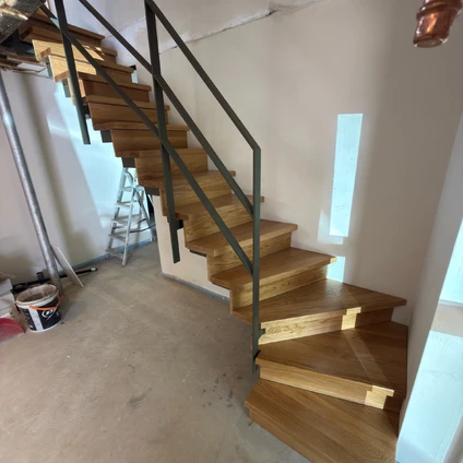 Schwarzes Geländer an einer ansteigenden Holztreppe in einem modernen Wohnambiente