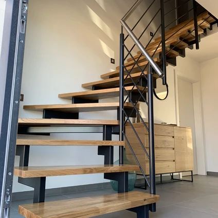 Moderne Holztreppe mit schwarzem Metallgeländer flankiert von einem hellen Holzschrank