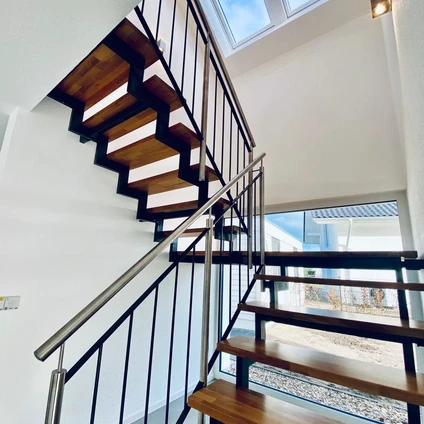 Moderne Holztreppe mit schwarzen Metallgeländern und glänzenden Edelstahlhandläufen in einem hellen Interieur