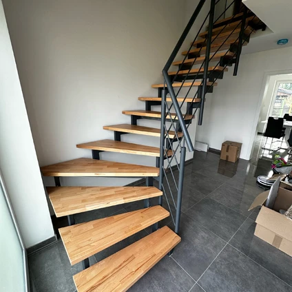Industrielle Holztreppe mit schwarzem Metallgeländer und dunklem Fliesenboden