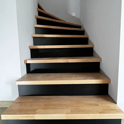 Moderne Treppe mit schwarzen Stufenrahmen und warmen Holztrittflächen