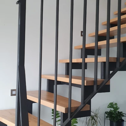 Minimalistische Wohnhaustreppe aus hellen Holzstufen und schwarzem Metallgeländer