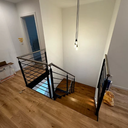 Moderne Treppe mit schwarzem Geländer und Glasakzenten in hellen Räumen