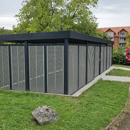 Moderne dunkle Gartenstruktur mit Gitterpaneelen auf grünem Rasen vor Bäumen