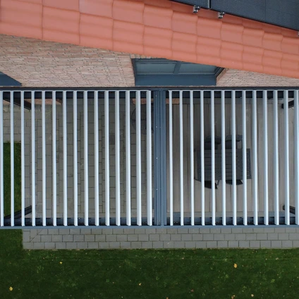 Hoher moderner Metallzaun mit Steinsockel vor einer Hausfassade in zwei Farben