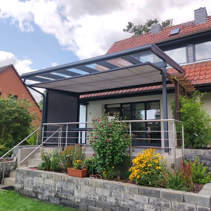 Überdachte moderne Terrasse mit Glasdach und Garten bestehend aus Stufen und Blumenbeeten
