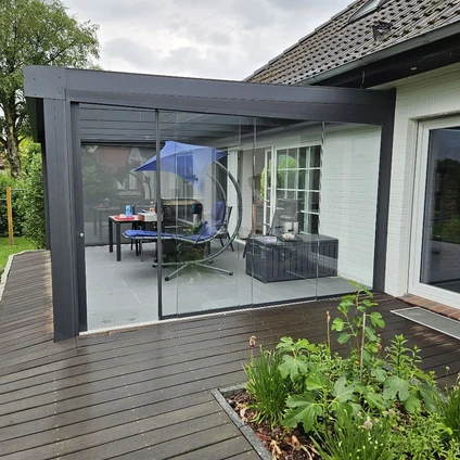 Moderne Verglasung eines Gartenbereichs mit Holzterrasse und Außenmöbeln