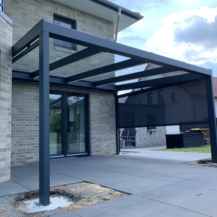 Dunkler Metallcarport mit modernem Design über einem Zuhause aus hellem Mauerwerk
