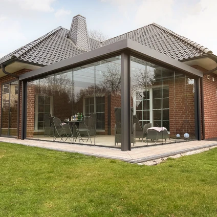 Moderne Glashaus-Verlängerung an Backsteinhaus mit Patio und angrenzender grüner Rasenfläche
