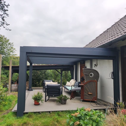 Dunkler überdachter Patio mit Lounge-Möbeln Grill und neuem Wohnbereich am Haus