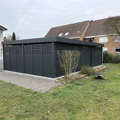 Moderne dunkelgraue Außenstruktur mit Lüftungsschlitzen auf einem Kiesweg vor einem Wohnhaus