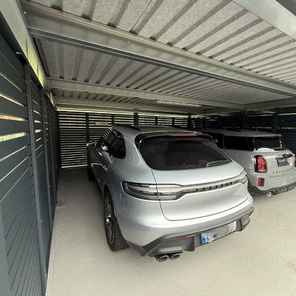 Silberner Minivan in überdachter Garage mit einem weiteren SUV im Hintergrund
