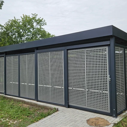 Reihe moderner dunkler Schuppen mit perforierten Metalltüren an einem gepflasterten Weg