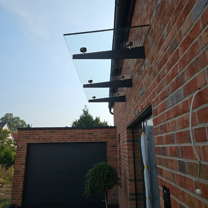 Modern Backsteinhaus mit einem schwebenden Glasbalkon der von schwarzen Metallhalterungen gehalten wird