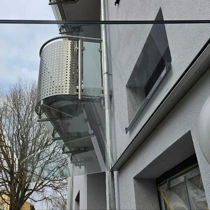 Moderne Hausfassade mit gekrümmtem Balkon Glasgeländer und schrägem Fenster