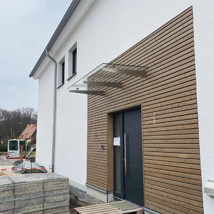 Modernes Haus mit weißer Fassade und warmen Holzverkleidungen am Eingangsbereich
